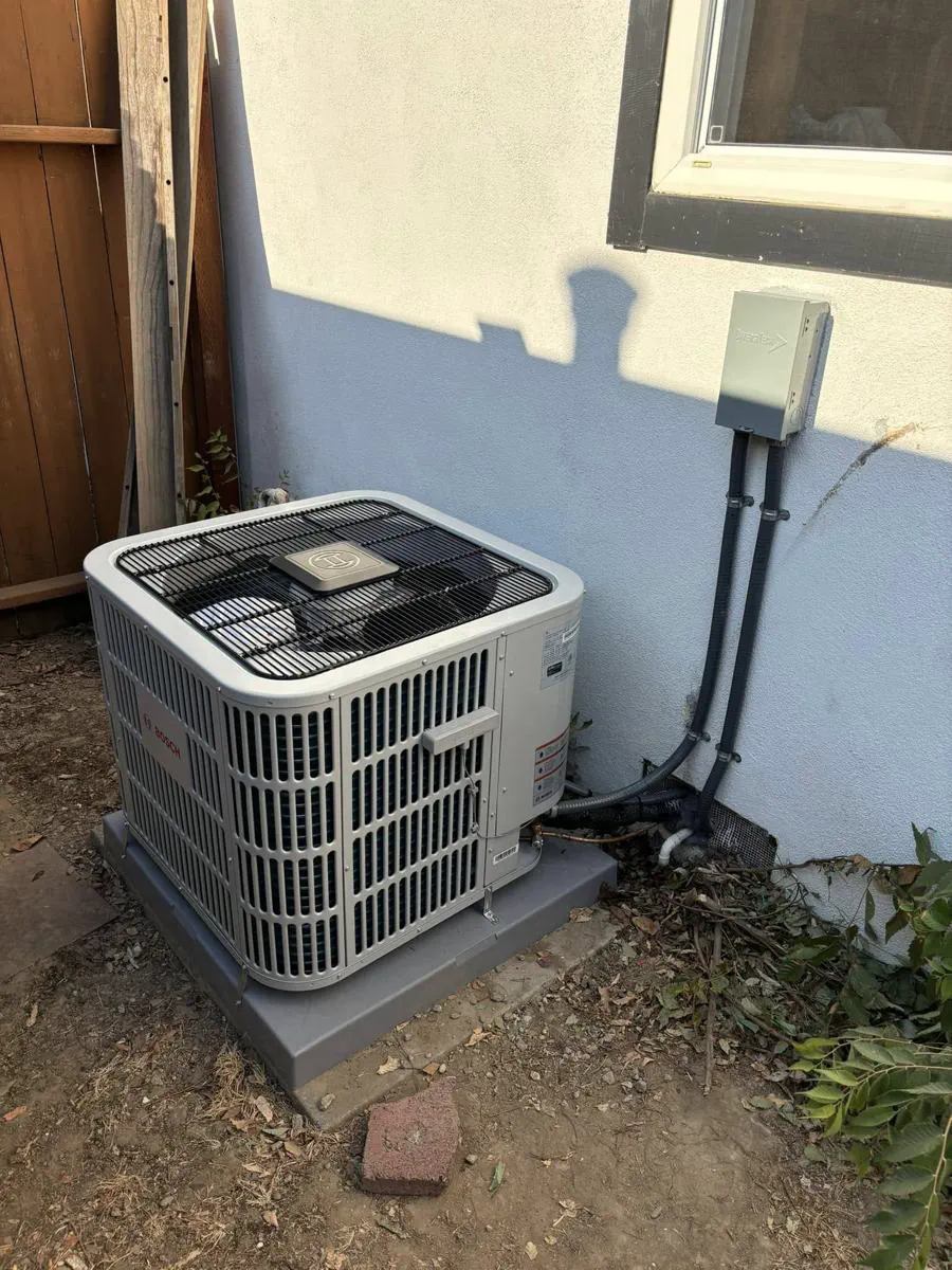 A new Bosch condenser installed against a stucco wall