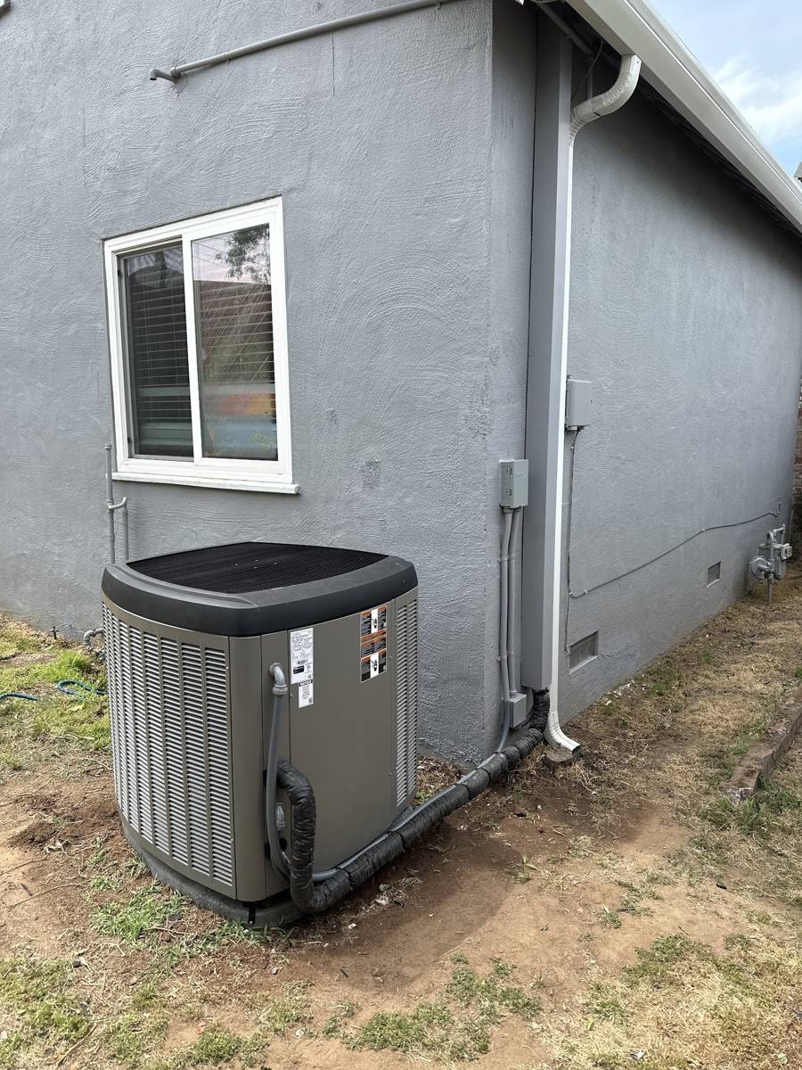 A condenser unit installed beside a window