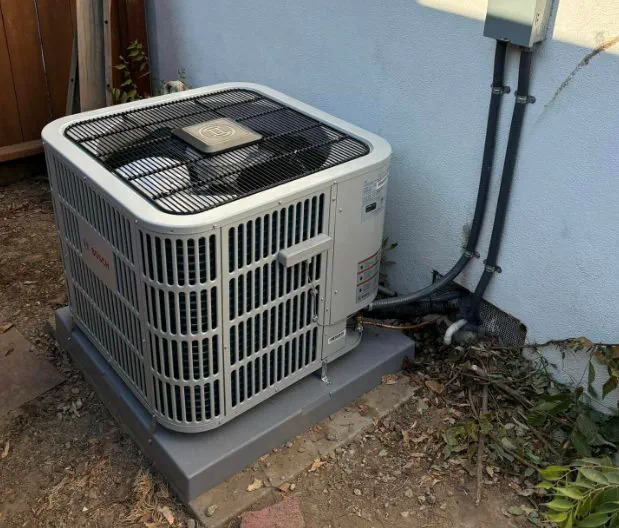 A Bosch heat pump condenser installed at the side of a house
