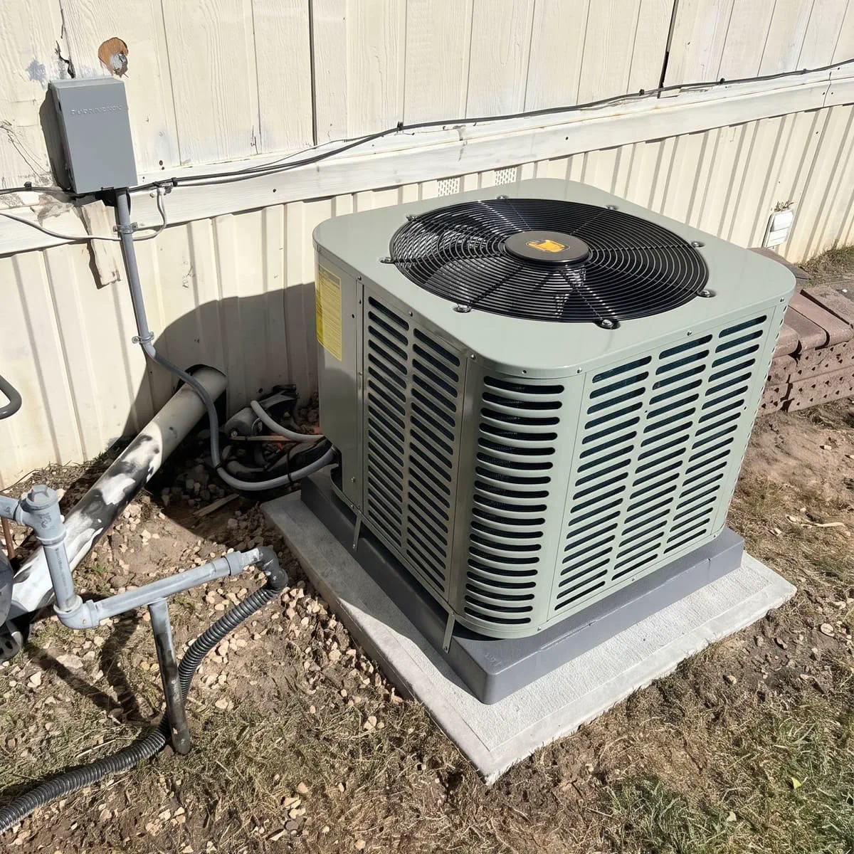 A newly installed outdoor condenser unit on a fresh concrete pad